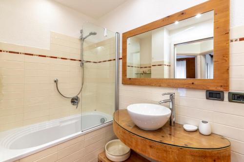 a bathroom with a sink and a tub and a mirror at Valle Maura in Canazei