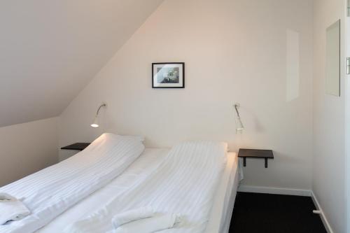 a white bedroom with two beds and a table at Skråvej Bed & Breakfast in Skagen