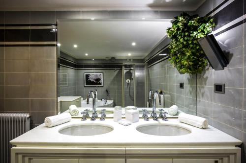uma casa de banho com 2 lavatórios e um espelho grande em EDO em Campitello di Fassa