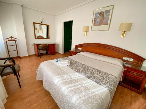 a bedroom with a bed and a table and a chair at Hotel Cardinal in Albacete