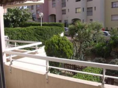a balcony with a white railing and bushes at Appartement Cap D'Agde in Cap d'Agde