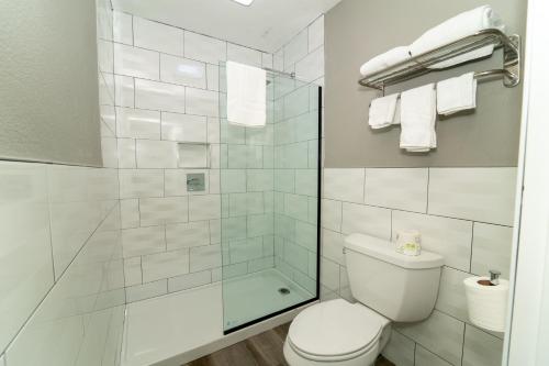 a bathroom with a toilet and a glass shower at Hollywood Palms Inns & Suites in Los Angeles