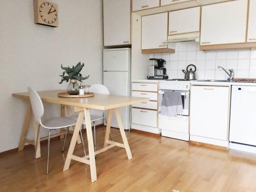 a kitchen with a table and chairs and a clock on the wall at Roost Pursimiehenkatu in Helsinki