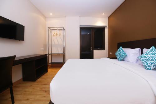 雅加達的住宿－Altona Hotel，卧室配有一张白色大床和一张书桌