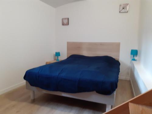 a bedroom with a bed with a blue blanket on it at Maison familiale avec jardin au coeur du d day in Port-en-Bessin-Huppain