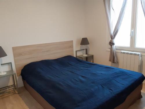 a bedroom with a bed with a blue blanket on it at Maison familiale avec jardin au coeur du d day in Port-en-Bessin-Huppain