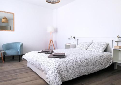 a white bedroom with a bed and a blue chair at Dunas Jewel Apartment in Morche