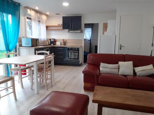 un salon avec un canapé rouge et une cuisine dans l'établissement L'inattendu du D-Day, à Port-en-Bessin-Huppain