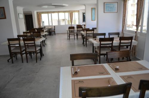 a dining room with tables and chairs and windows at Grand Milano Hotel in Ayvalık