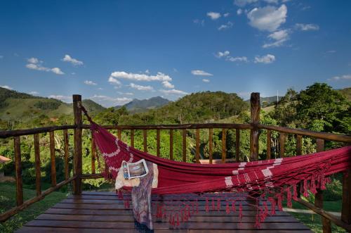 a hammock on a wooden bridge with mountains in the background at Pousada Lua de Minas in Visconde De Maua