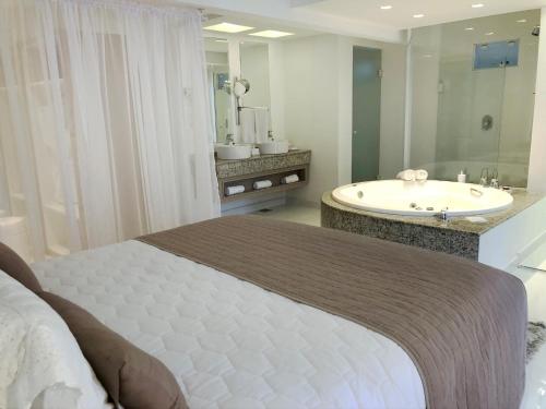 uma casa de banho com uma cama, uma banheira e um lavatório. em Hotel Rieger no Balneário Camboriú