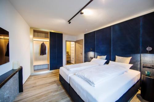 1 dormitorio con 1 cama grande y pared azul en All.Glemm RIDERS SUITE, en Saalbach Hinterglemm