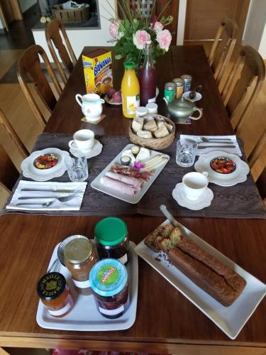 a wooden table topped with plates of food at chambre d'hôtes de charme, un temps en forêt in Westhouse