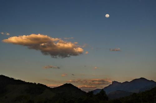 a sunset with the moon in the sky over mountains at Pousada Lua de Minas in Visconde De Maua