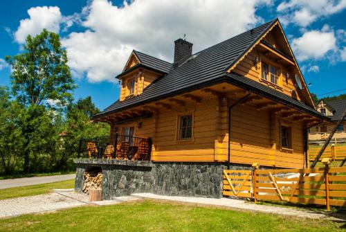 a large wooden house with a porch on it at Chatka Pod Laskiem - Domki w górach in Soblówka