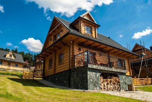 a log cabin with a wrap around porch at Chatka Pod Laskiem - Domki w górach in Soblówka