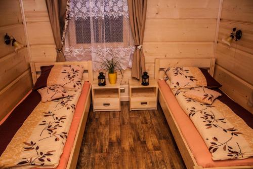 two beds in a room with a window at Chatka Pod Laskiem - Domki w górach in Soblówka