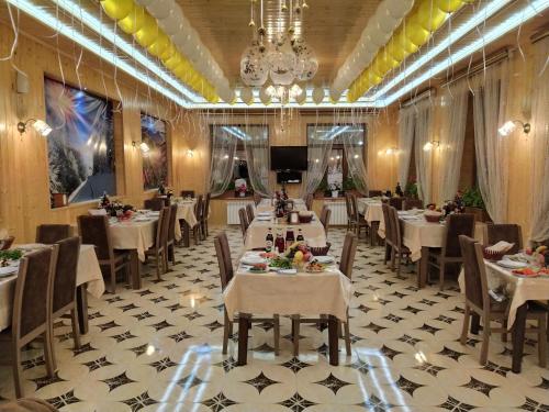 un restaurant avec des tables et des chaises blanches et un lustre dans l'établissement Selena, à Qusar