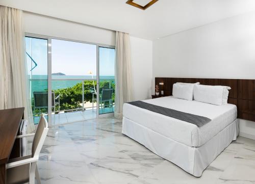 a bedroom with a bed and a view of the ocean at Itacolomi Hotel in Piçarras