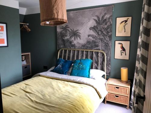 a bedroom with green walls and a bed with blue pillows at Boutique home near Chichester centre in Chichester