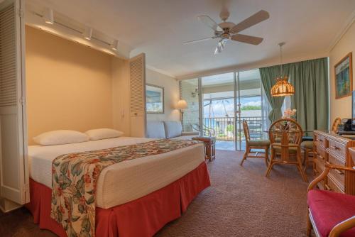 a hotel room with a bed and a balcony at Napili Sunset Beach Front Resort in Lahaina