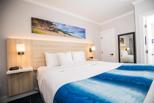 a bedroom with a large bed with a blue blanket at Comfort Inn Carmel By the Sea in Carmel