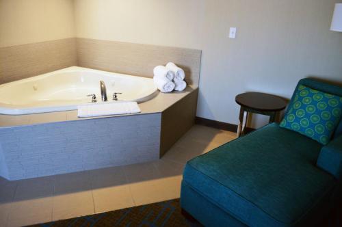 a hotel room with a tub and a chair at Holiday Inn & Suites Syracuse Airport - Liverpool by IHG in Liverpool