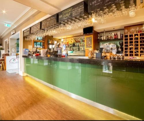 a bar with a green counter in a restaurant at The Redstones Hotel & Restaurant in Glasgow