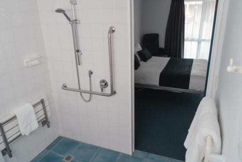 y baño con ducha, cama y espejo. en Fergussons Motor Lodge en  Waipukurau