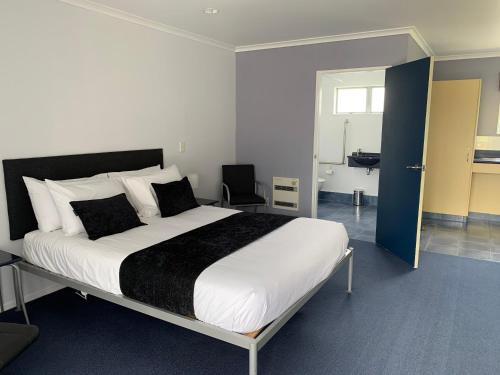 a bedroom with a large bed and a bathroom at Fergussons Motor Lodge in  Waipukurau