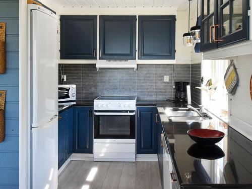 a kitchen with blue cabinets and white appliances at 9 person holiday home in Farstad-By Traum in Farstad