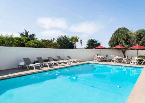 a swimming pool with chairs and umbrellas at Motel 6 San Simeon, CA - Hearst Castle Area in San Simeon