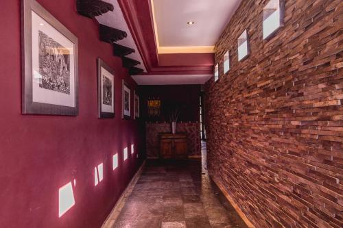 a hallway with a red brick wall with pictures at Casa Eva Hotel Boutique & Spa in Cholula