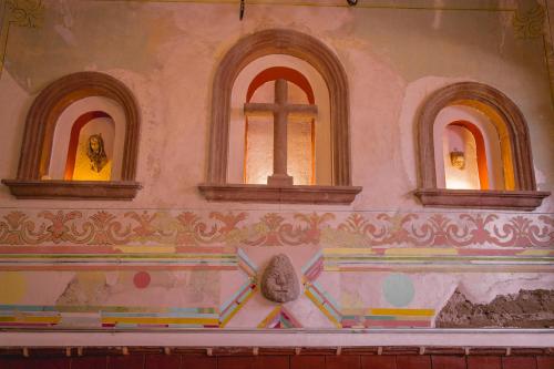 a church with three windows and a statue on a wall at Casa Eva Hotel Boutique & Spa in Cholula