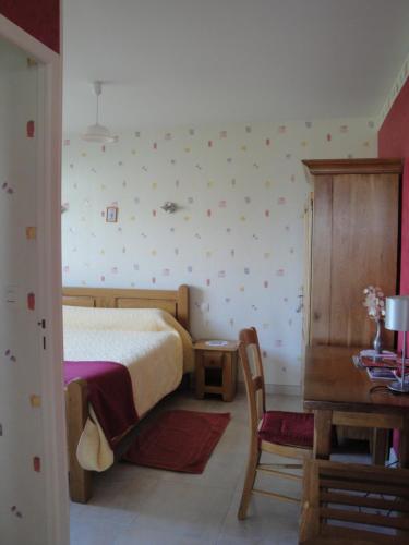 a bedroom with a bed and a table and a chair at Ferme de La poterie in Donnery