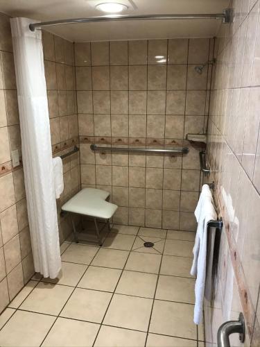 a tiled bathroom with a toilet and a bench at Economy Inn LAX Inglewood in Inglewood