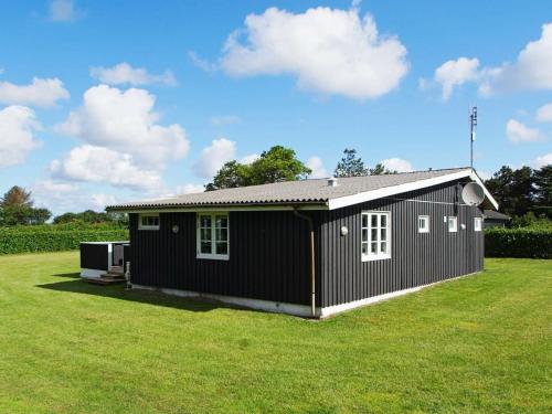 a small black house on a grass field at 8 person holiday home in Hemmet in Hemmet