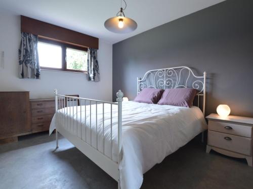Un dormitorio con una cama blanca con almohadas moradas y una ventana en Lovely Holiday Home in Merksplas with Fenced Garden, en Merksplas