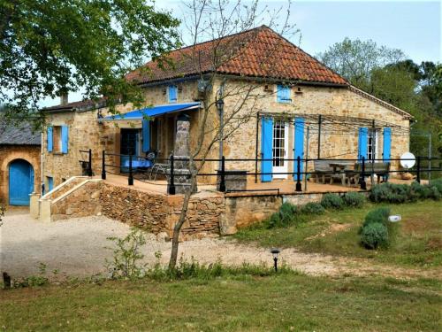 a stone house with blue windows and a patio at Authentic holiday home with private pool in Puy-lʼÉvêque