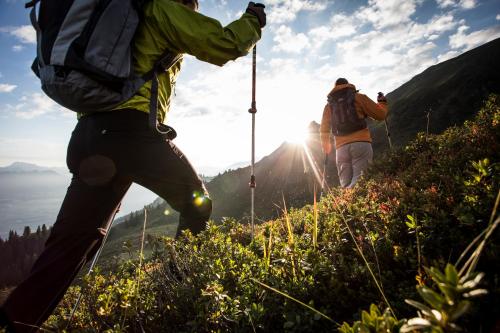 two people hiking on a mountain with the sun in the background at Gazauner Hof in Sankt Gallenkirch