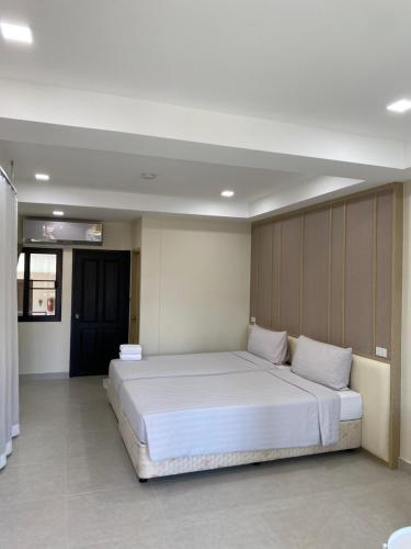 um quarto com uma grande cama branca num quarto em The Shade Residence em Pattaya Central
