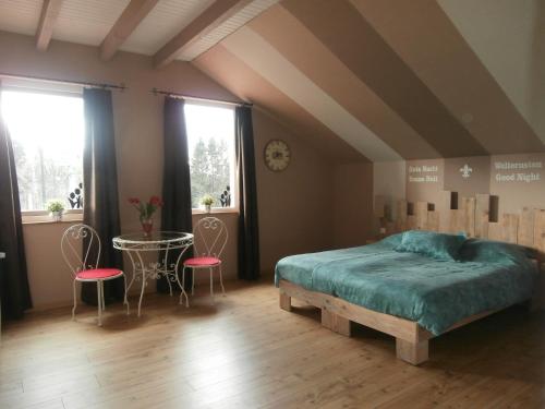 1 dormitorio con 1 cama, 1 mesa y 2 sillas en Chambres d'Hôtes La Tulipe, en Champdray