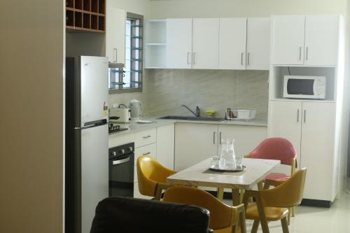 FIJI HOME Apartment Hotel في سوفا: مطبخ مع دواليب بيضاء وطاولة مع كراسي