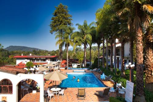 una piscina al aire libre con palmeras y un complejo en Hotel El Rebozo en Valle de Bravo