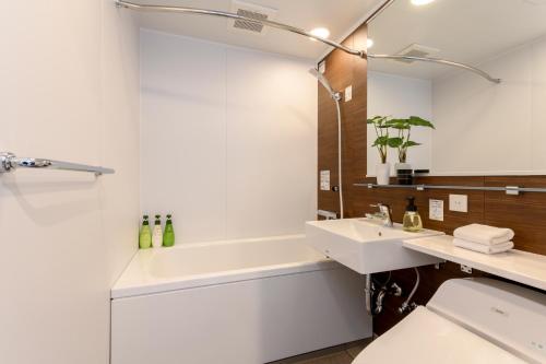 La salle de bains est pourvue d'un lavabo, d'une baignoire et de toilettes. dans l'établissement SnowDog Village, à Niseko