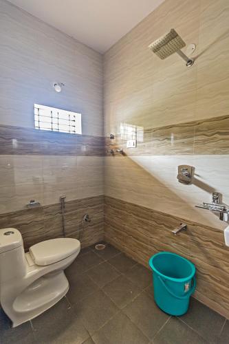 a bathroom with a toilet and a sink and a bucket at Krishna Homestay Hampi in Hampi