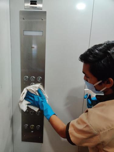 a man wearing a mask and gloves putting something into an elevator at Hotel Abika Elite in Ujjain