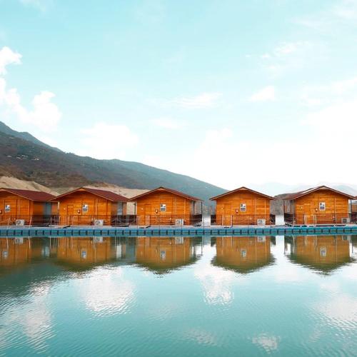 a row of houses sitting on top of a body of water at Le ROI Floating Huts & Eco Rooms Tehri in Tehri-Garhwāl
