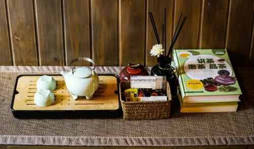 uma mesa com uma bandeja com um bule de chá e livros em Lv Ye An Jia 绿野安家 em Lijiang