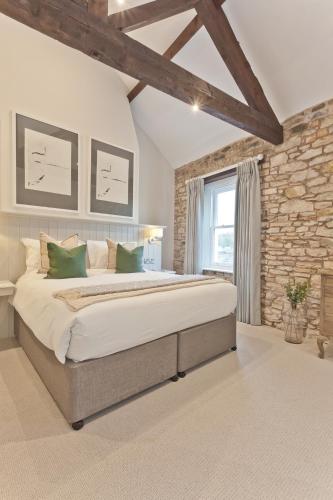 a bedroom with a large bed and a stone wall at Tithe Barn - Self Check In Hotel in Cockermouth